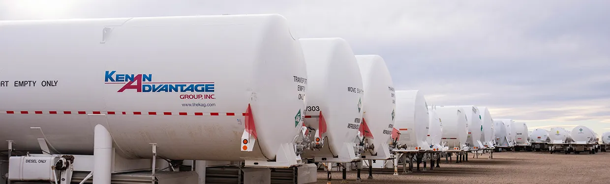 Row of Kenan Advantage Group white cryogenic tanker trailers marked Transport Empty Only parked in an outdoor lot