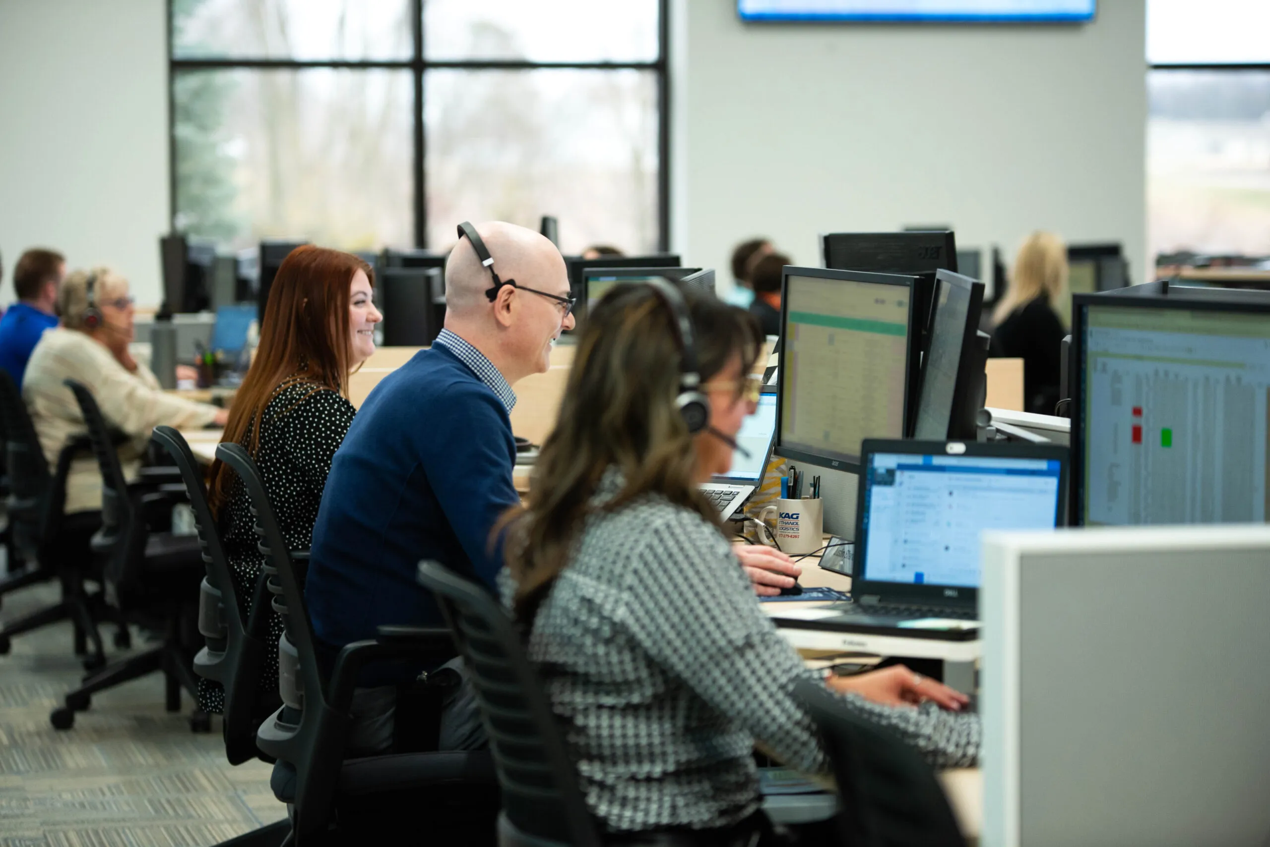 KAG employees collaborating at workstations in a busy logistics office