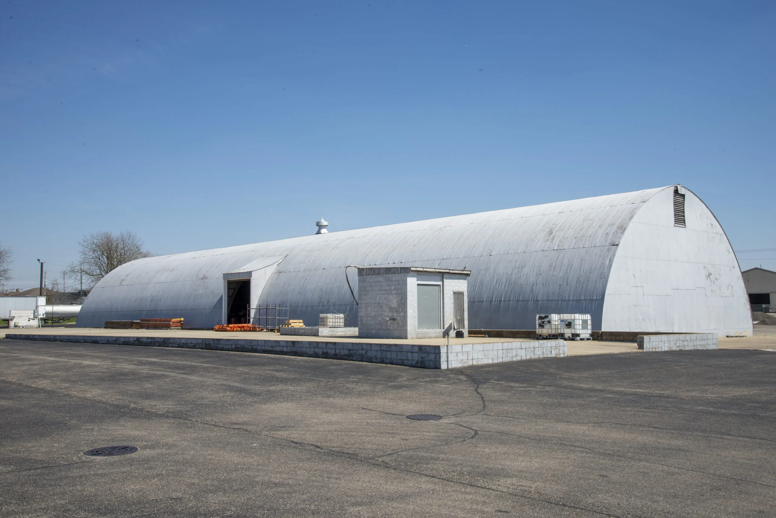 Exterior view of a large arched industrial warehouse building on a clear day