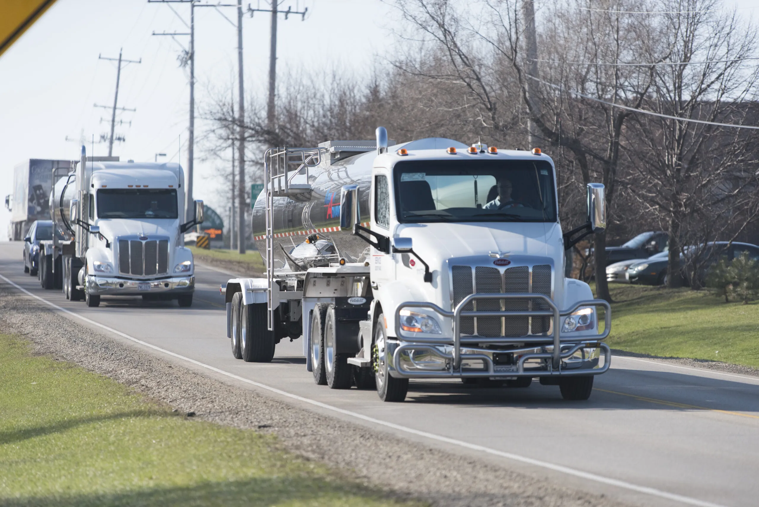Two KAG Specialty Products Group tanker trucks traveling in convoy on a rural road
