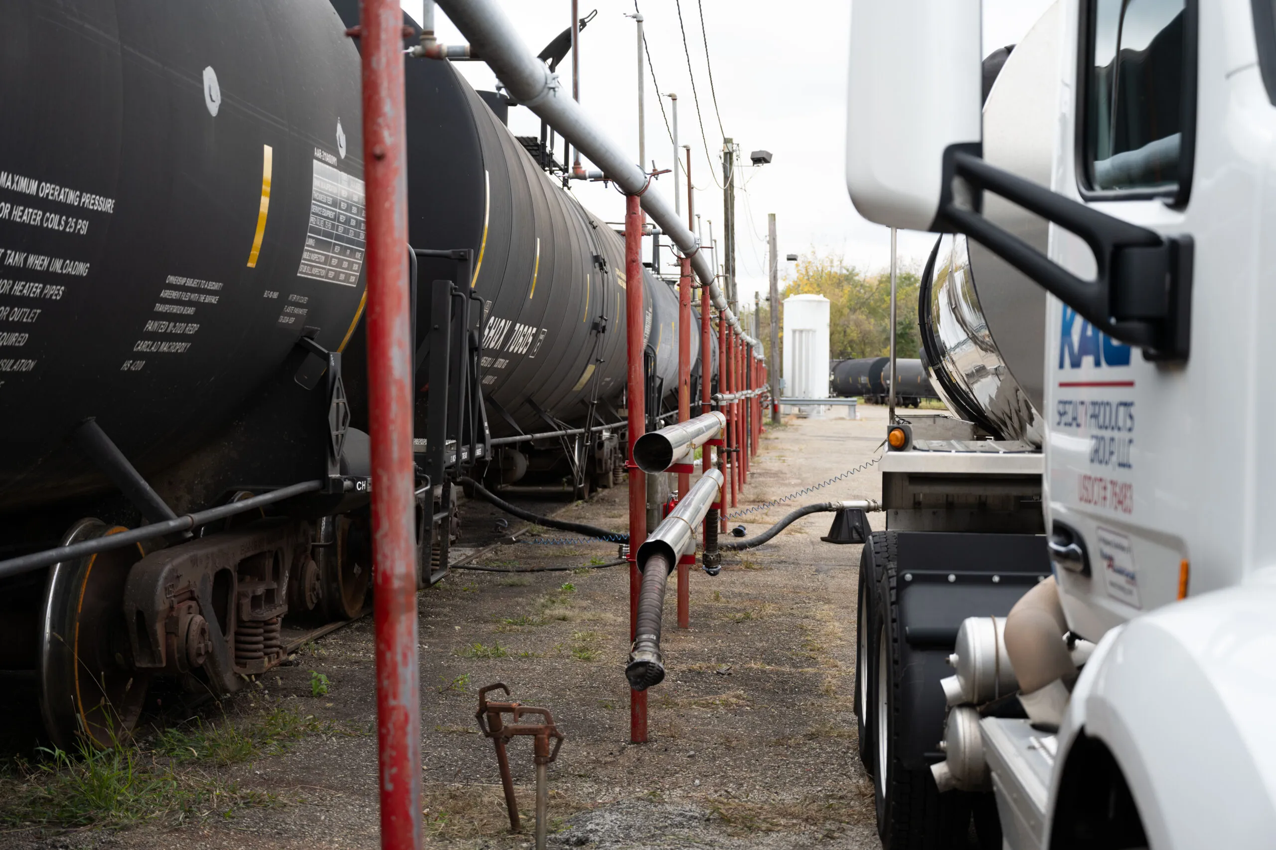 KAG tanker truck loading product alongside railcars at a transloading site