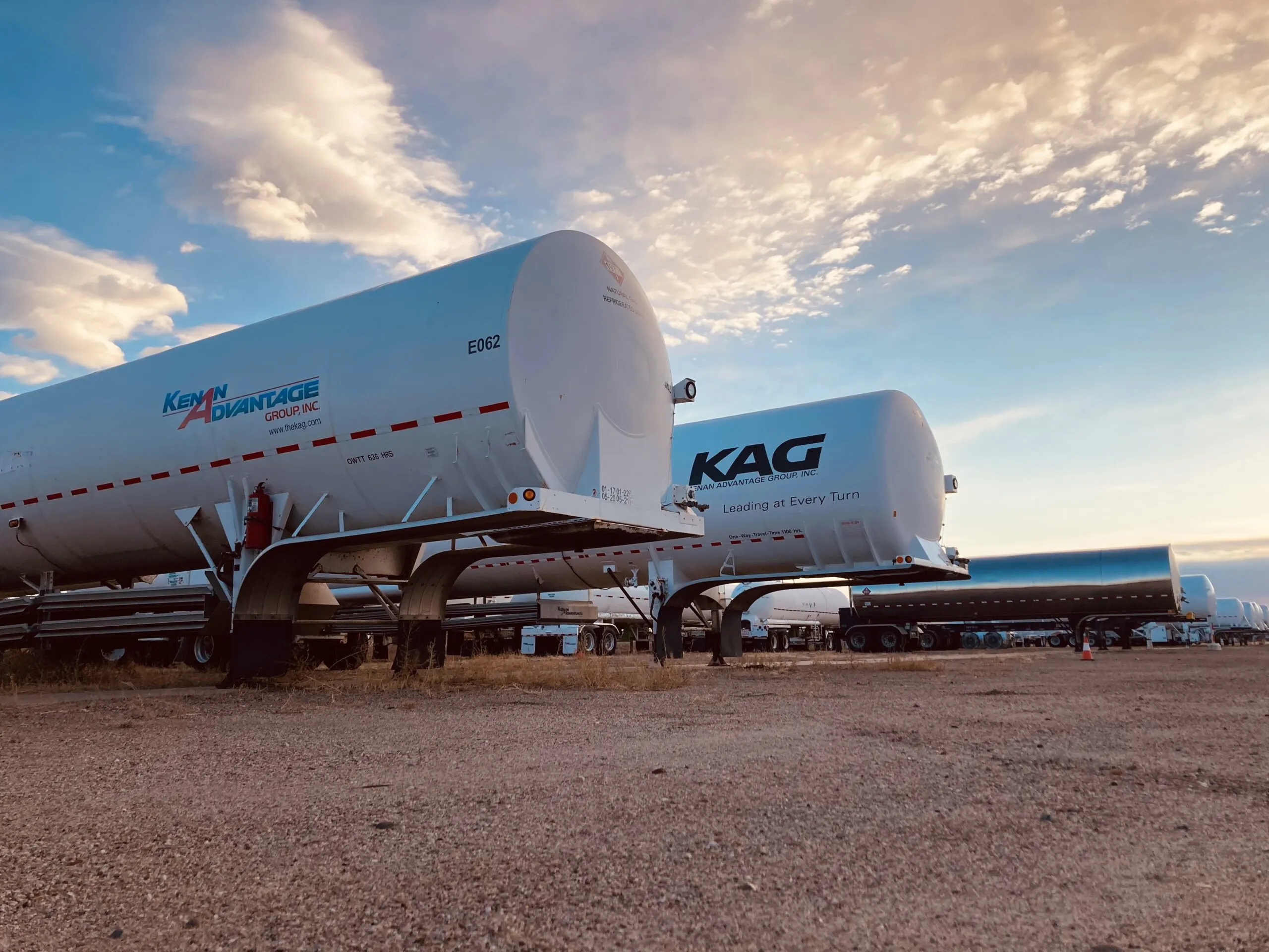 Row of KAG Kenan Advantage Group tanker trailers parked at a lot at sunset