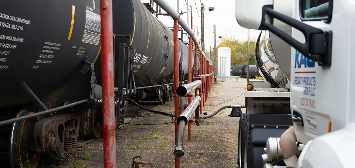 Railcar transloading operation with tanker railcars and a vacuum truck transferring liquid product at an industrial rail terminal.