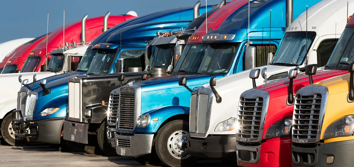 Row of colorful semi-truck cabs lined up at a truck lot