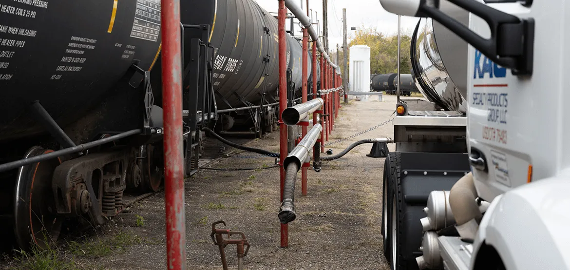Railcar transloading operation with tanker railcars and a vacuum truck transferring liquid product at an industrial rail terminal.