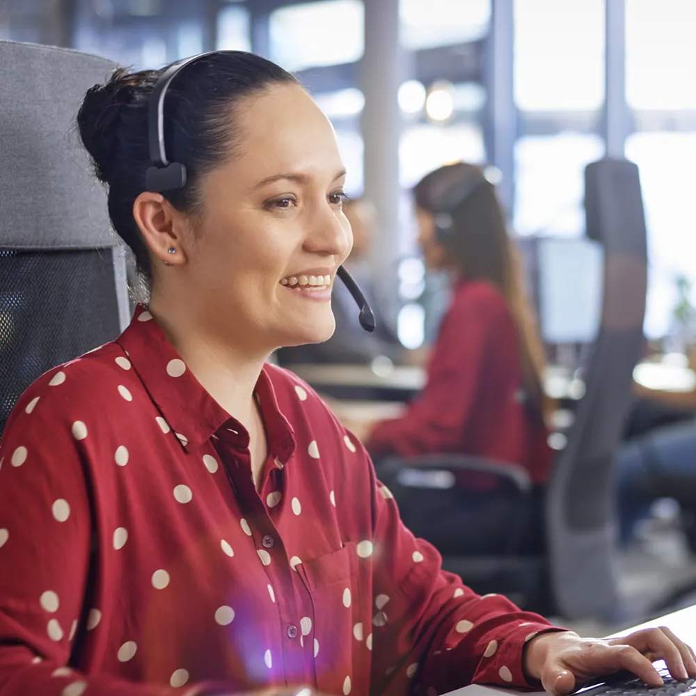 Customer service representative wearing a headset assisting clients in a transportation and logistics support center.
