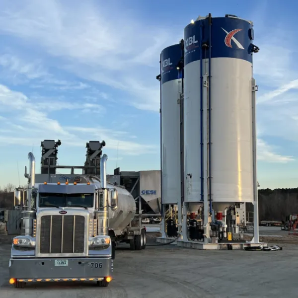 Bulk storage and distribution facility featuring vertical storage silos and a tanker truck positioned for liquid product loading and unloading operations.
