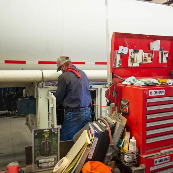 KAG mechanic working on a tanker trailer beside a tool chest in a shop