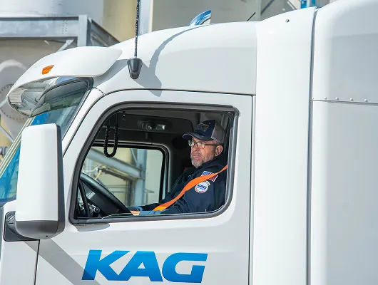 KAG driver seated in the cab of a KAG-branded truck looking out the window