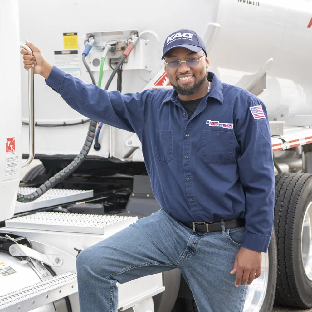 KAG dedicated fleet driver standing beside a commercial tanker truck, representing professional transportation and bulk liquid delivery services.