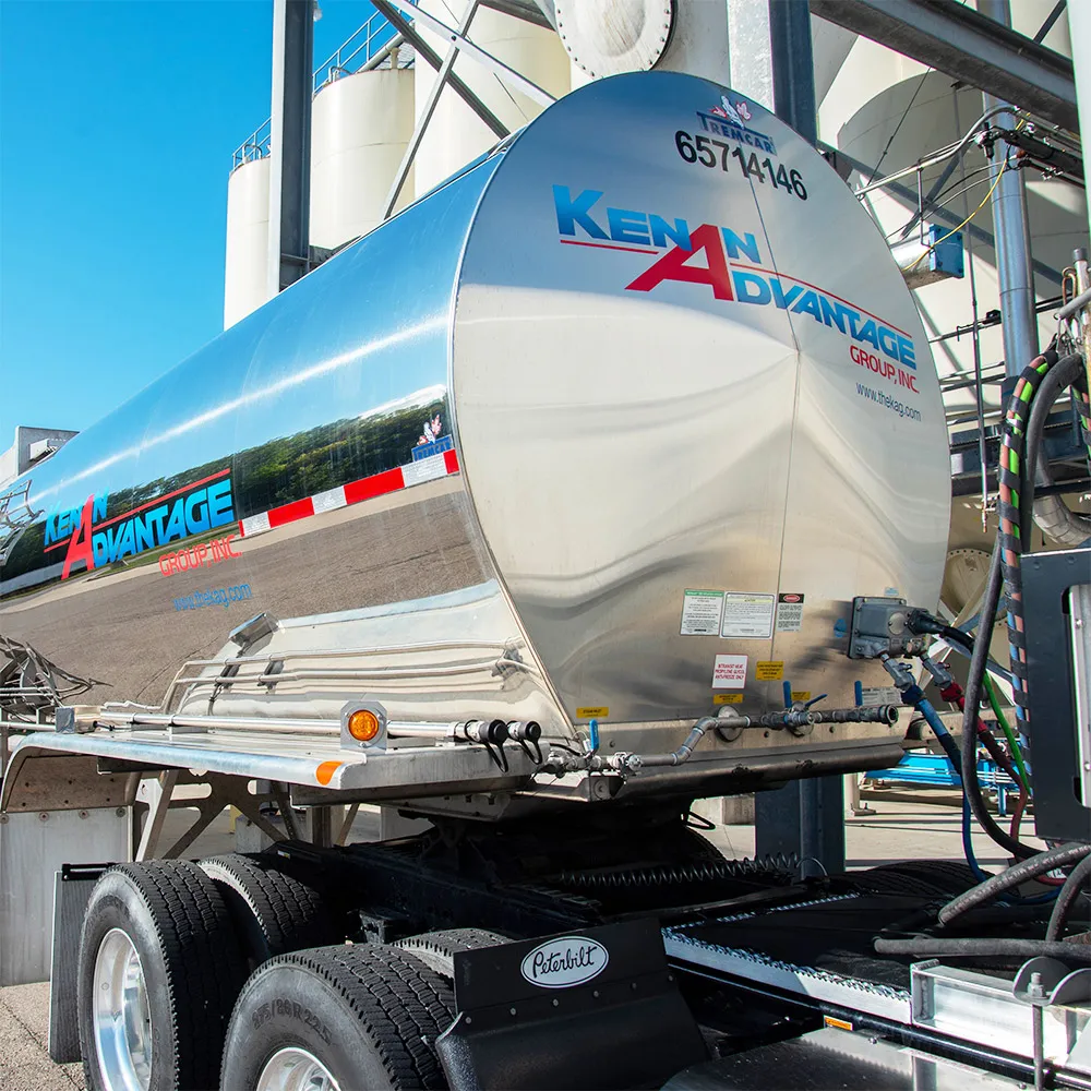 KAG stainless-steel tanker trailer connected at an industrial loading facility, supporting dedicated bulk liquid transportation and distribution operations.