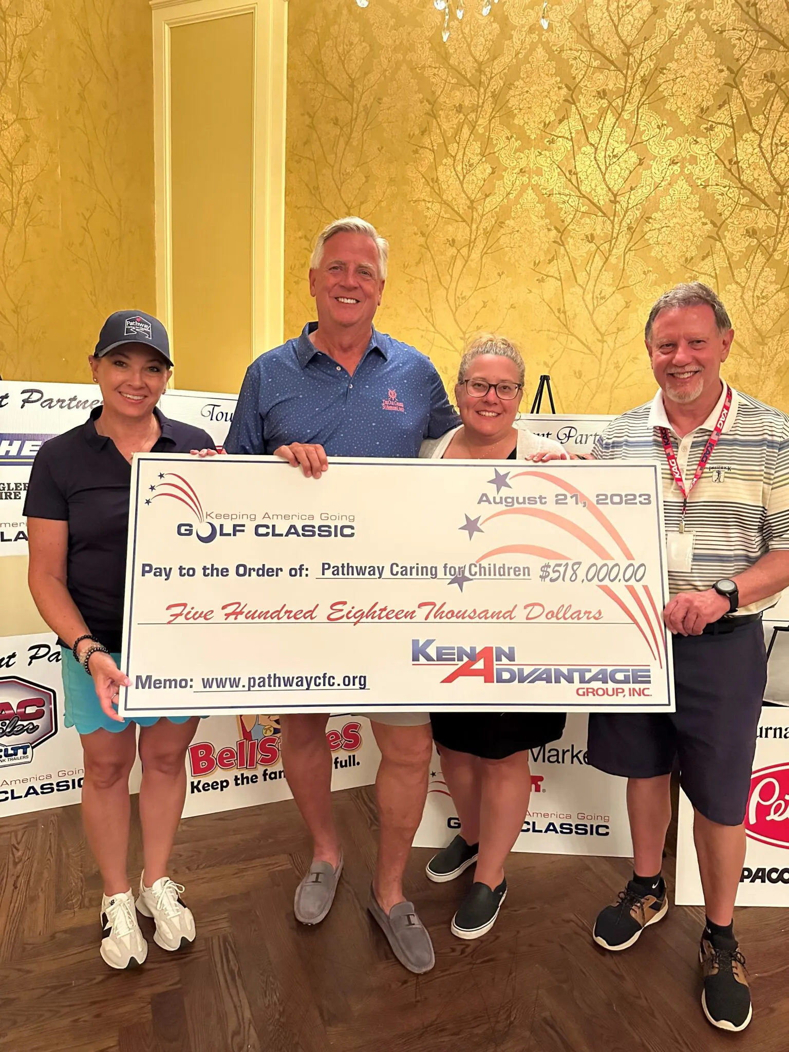 Four people holding a giant $518,000 check for Pathway Caring for Children at a golf classic