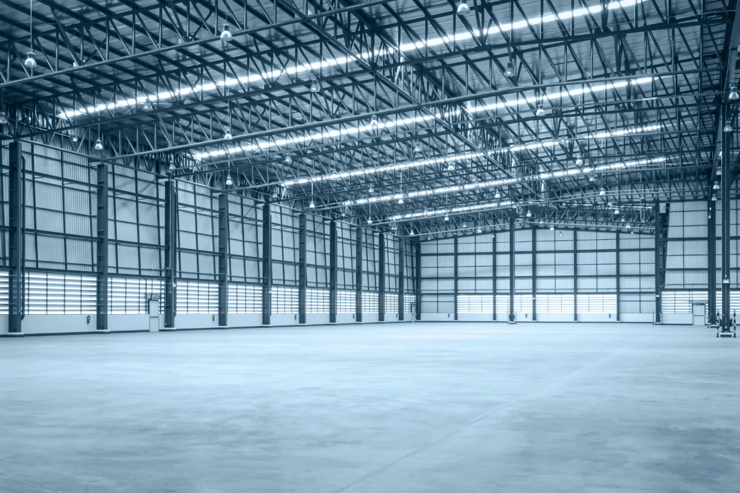 Large modern warehouse interior with high ceilings, industrial lighting, and open storage space designed for warehousing and distribution operations.