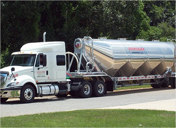 Evergreen Transport LLC trailer on a road lined with trees